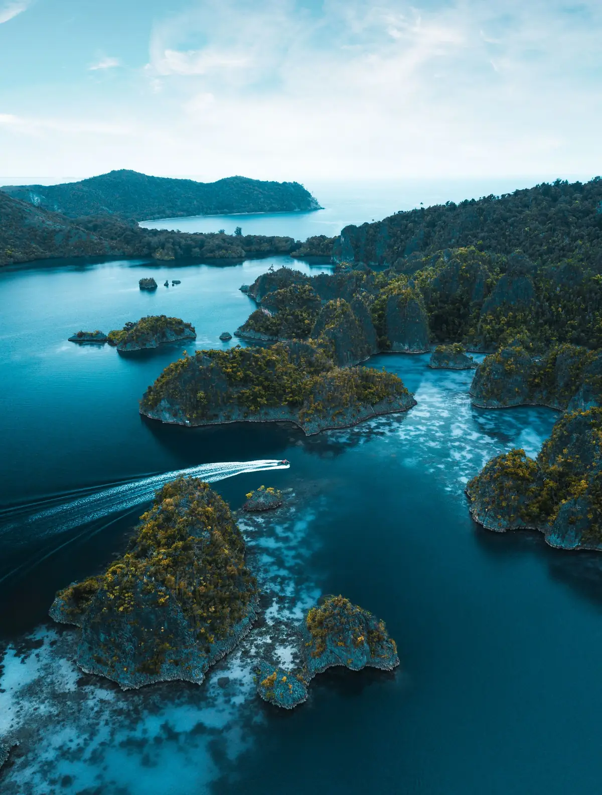 Aerial view of forested karst islets and shallow turquoise lagoons in Raja Ampat
