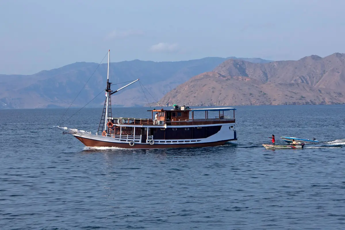 Traditional Indonesian phinisi charter vessel at anchor near Komodo Island with a tender alongside