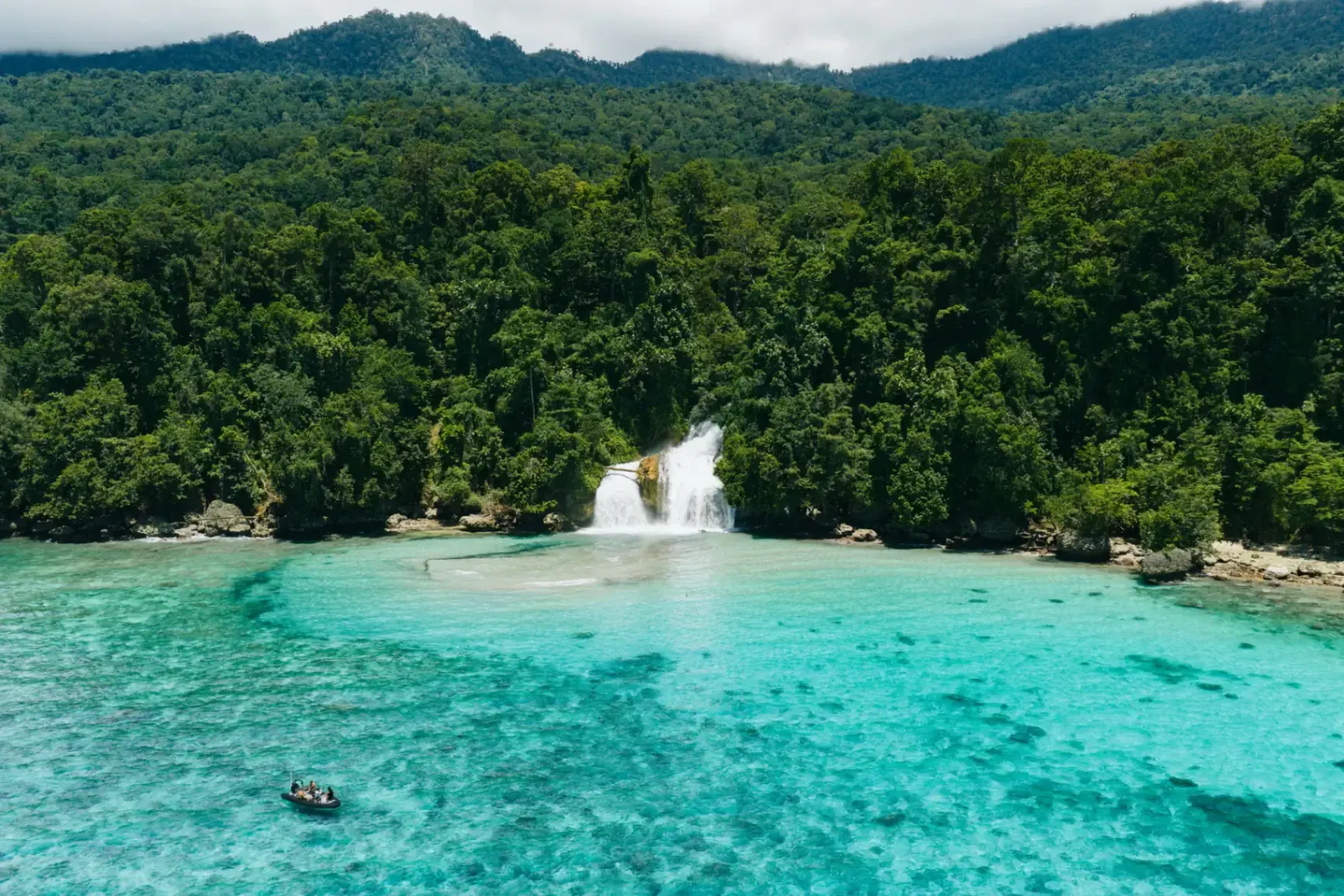 Tropical waterfall flowing into turquoise ocean Raja Ampat