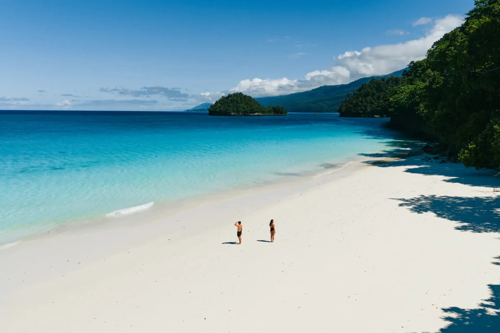 Couple on pristine white sand beach Raja Ampat